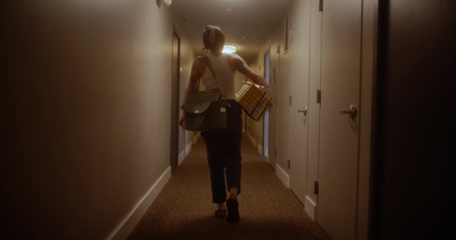 Woman with a backpack and a box walking down a hallway