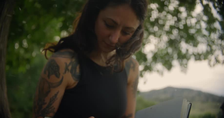 Woman sitting under a tree with an open notebook in her hands