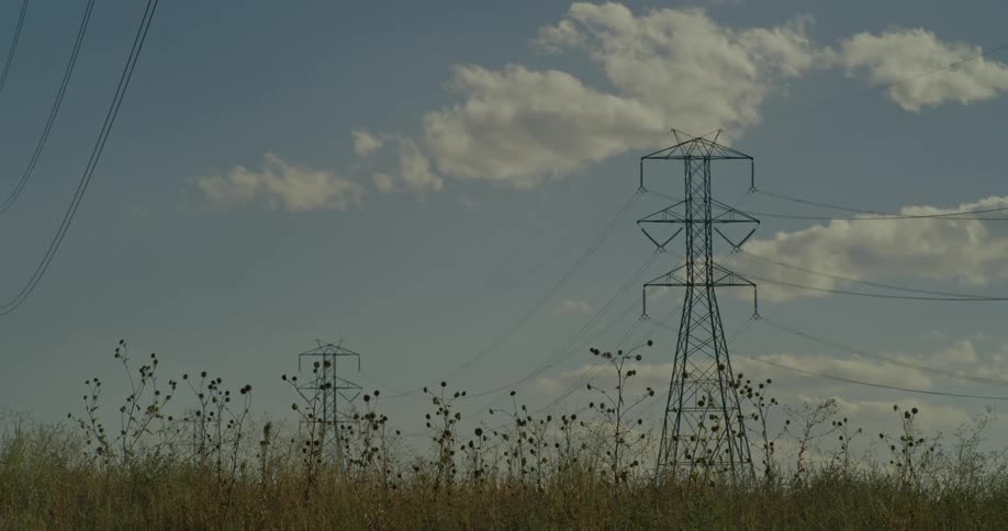 Wind blows the grass under the power lines