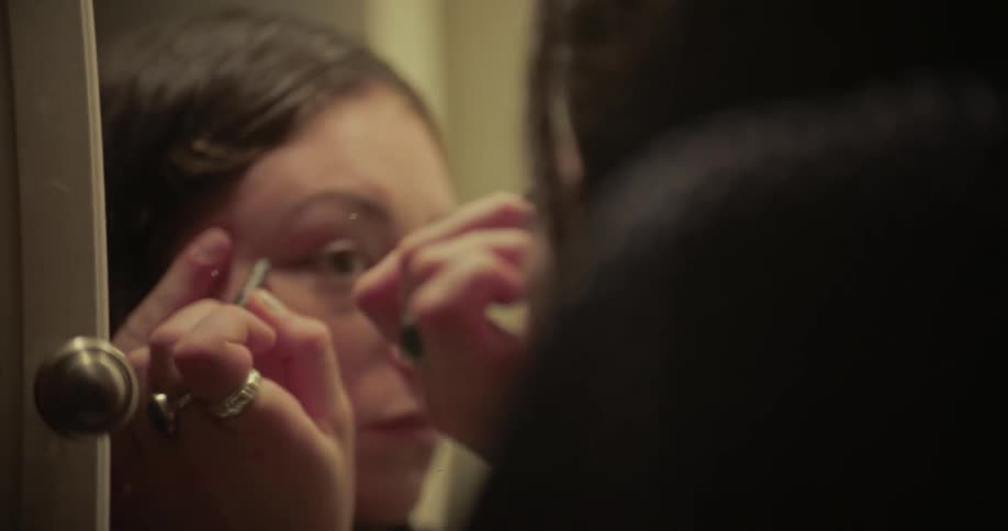Portrait of a woman applying makeup in front of the mirror