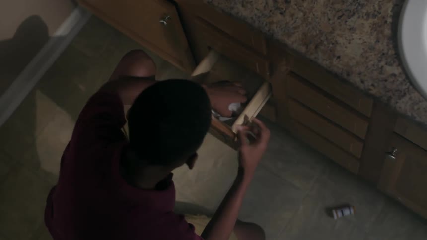 A teenager searches frantically through bathroom drawers