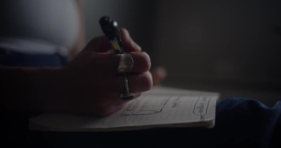 A person is drawing on a notepad with a pen