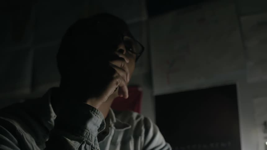 A man sits in a dark room pondering