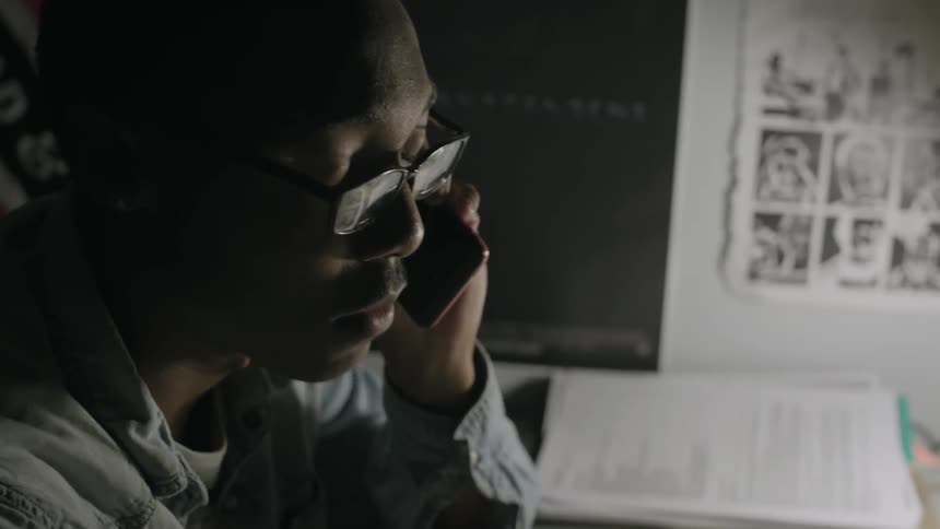 A man sits at a desk talking on the phone