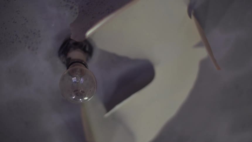A view of a light bulb through a broken shade