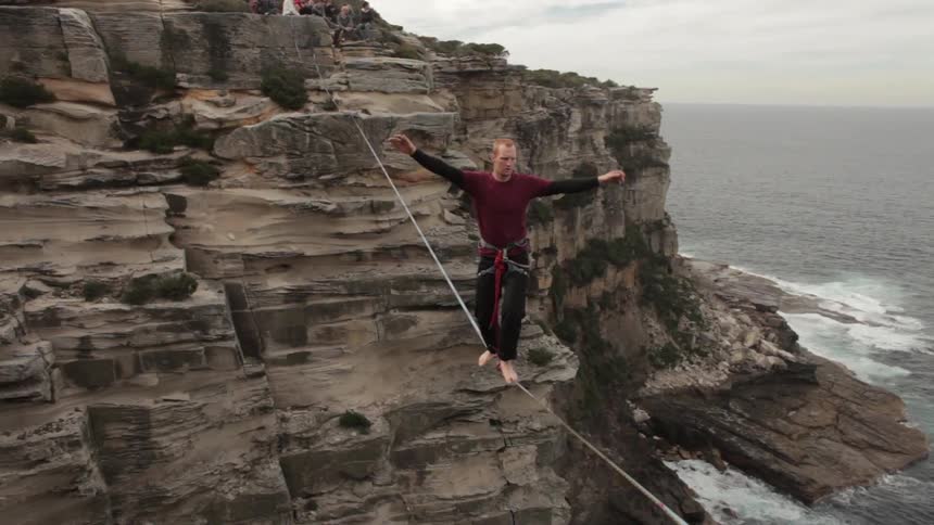 A man balancing on a tightrope in a canyon