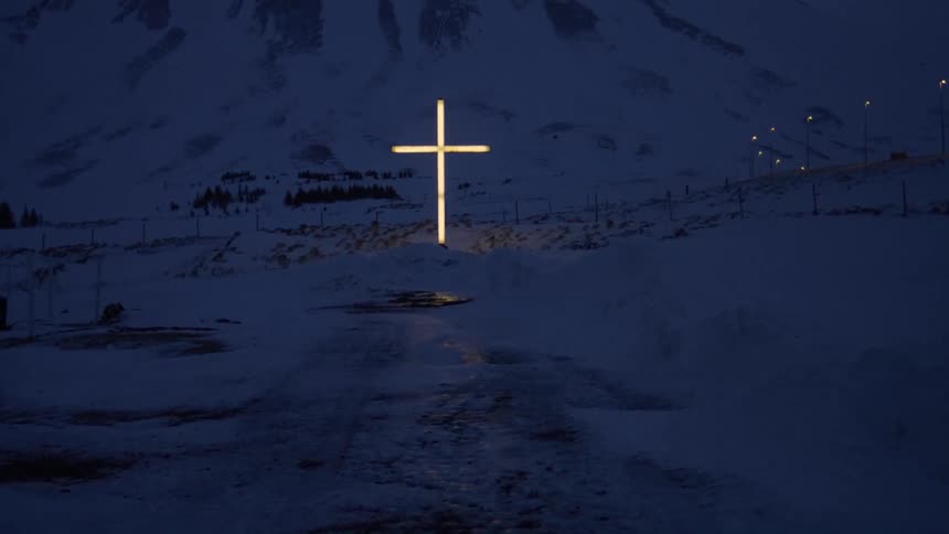 A glowing cross is in front of the mountain