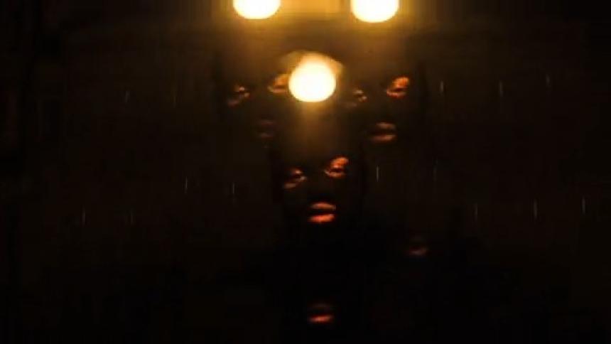 A man in a balaclava in the back of a van, a light swings above his head, a prism distorts the image