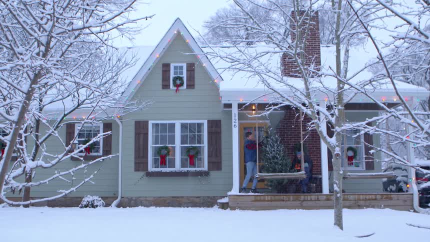 Father brings a christmas tree to his family and shakes off the excess snow on a snowy winter day