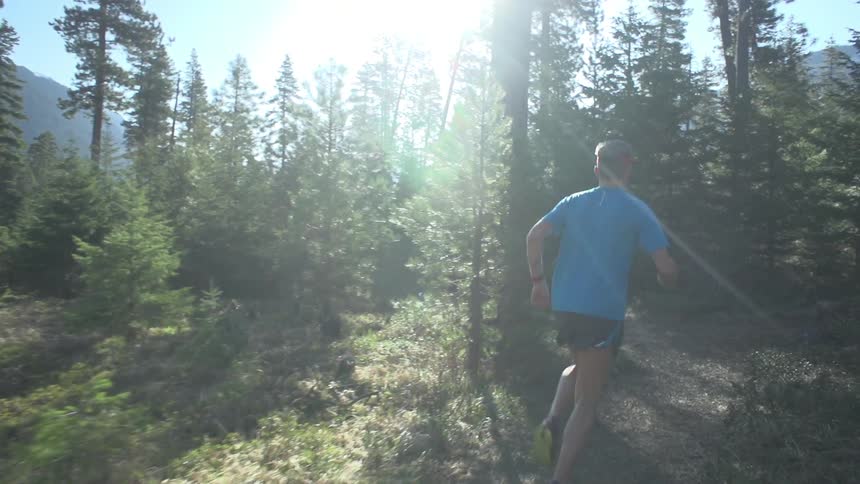 Man running down a trail on a sunny day