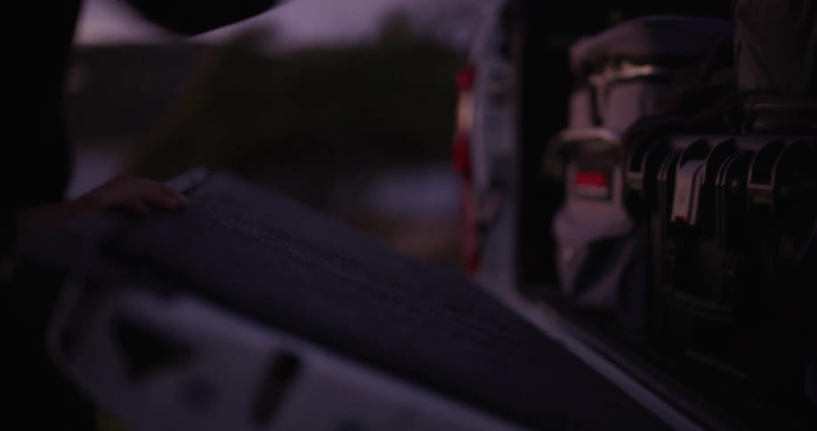 Hand opening the trunk of a pickup truck and taking out an object