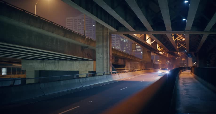 Vehicle drives through the city on the lower level of a multilevel highway during a foggy evening