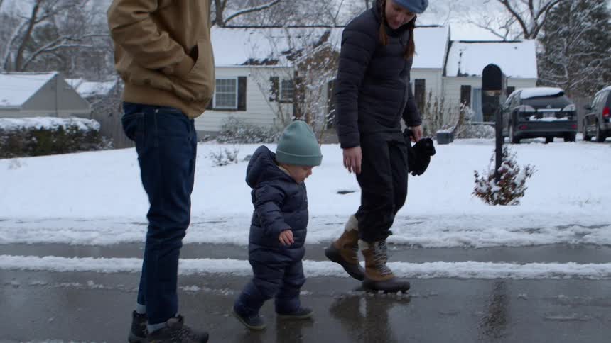 Parents help their son walk on the icy road