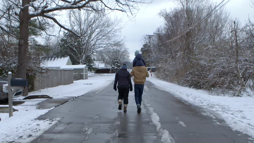 A family takes a walk down a residential street on a cloudy winter day