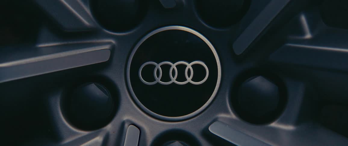 A closeup view of an audi car wheel hub prominently featuring the audi logo with four interlocking rings at the center