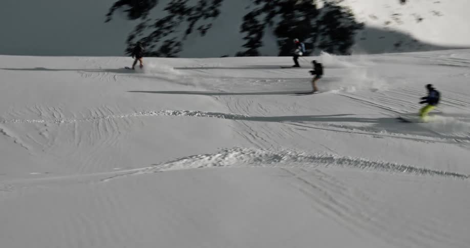 Skiers skiing down a slope as a helicopter flies above