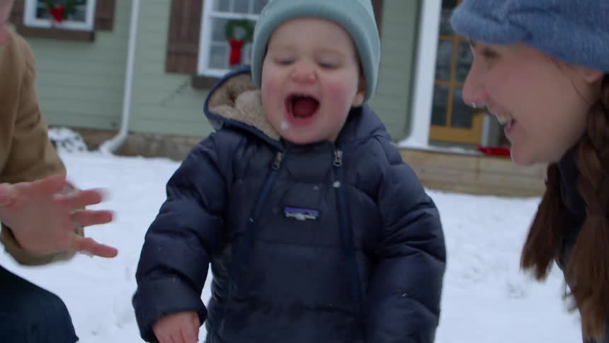 Little boy next to his parents throwing a snowball on the ground