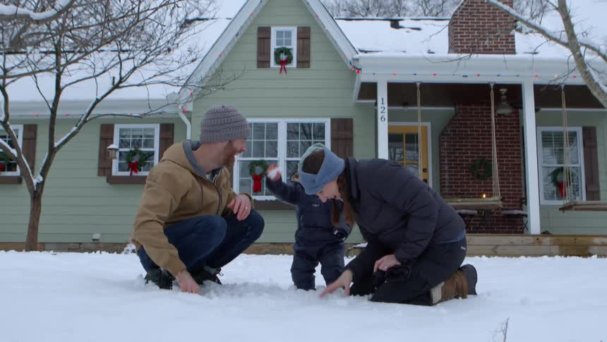 A mother and father play in a snowball fight with their toddler son on a winter day