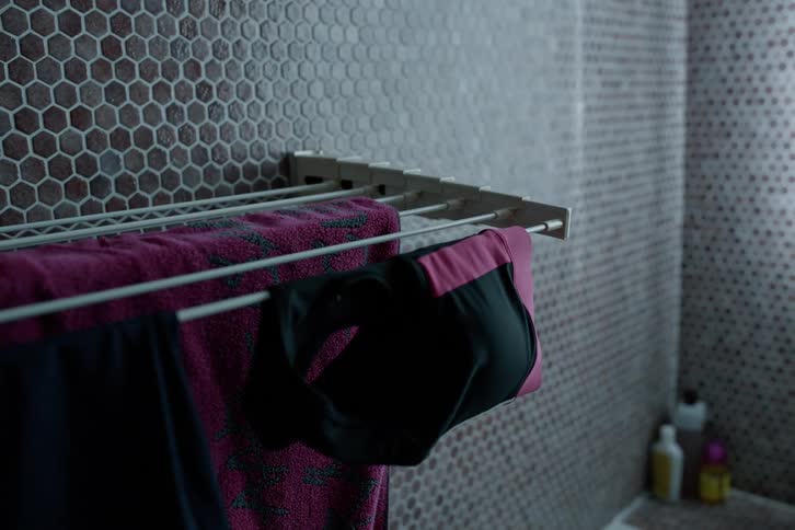 Pair of hands picking up a piece of clothing from a clothesline in an indoor space
