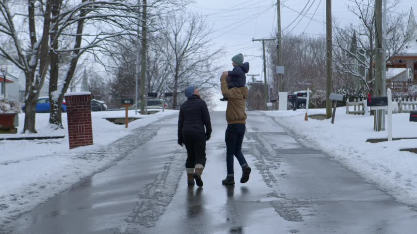 Family with a baby strolling through the neighborhood covered in snow