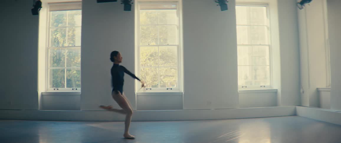 A ballerina performs a jump in a ballet studio on a sunny summer day