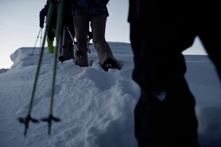 Four people in ski gear climbing a snowy mountain