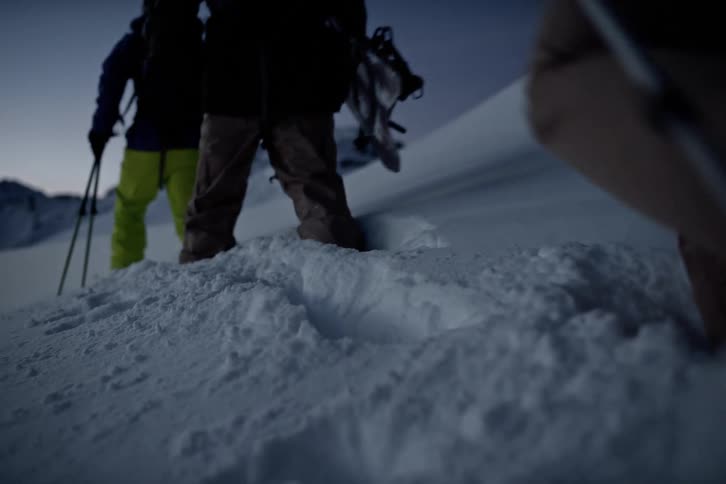 Legs of four people walking in the snow with ski equipment