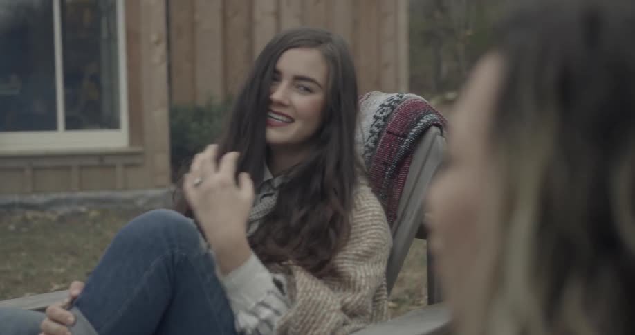 Two women drink hot beverages outside on a chilly day