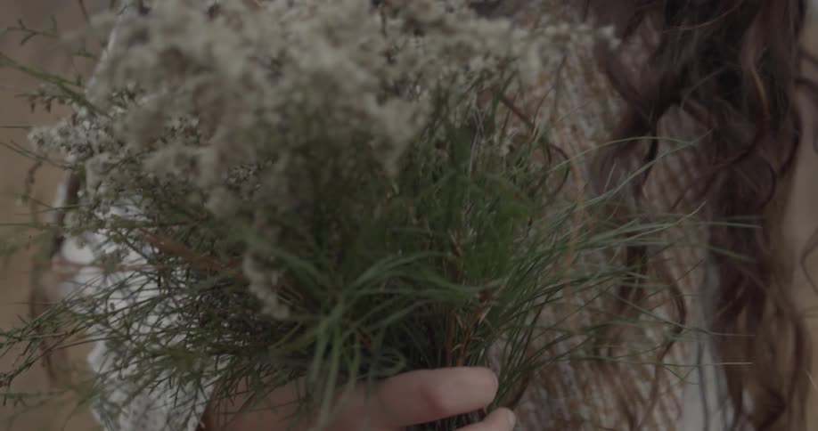 A dark haired woman holds a bundle of white flowers