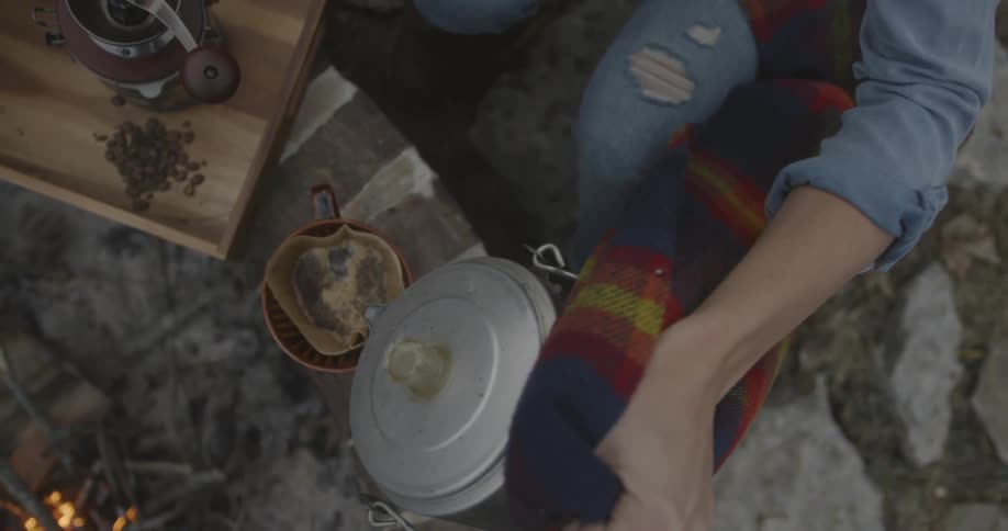 A woman pours hot water over coffee in a filter