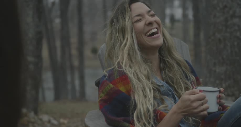 Woman laughs while holding a steaming mug