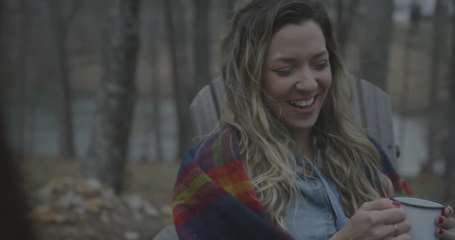A woman is laughing as she talks with a friend outside