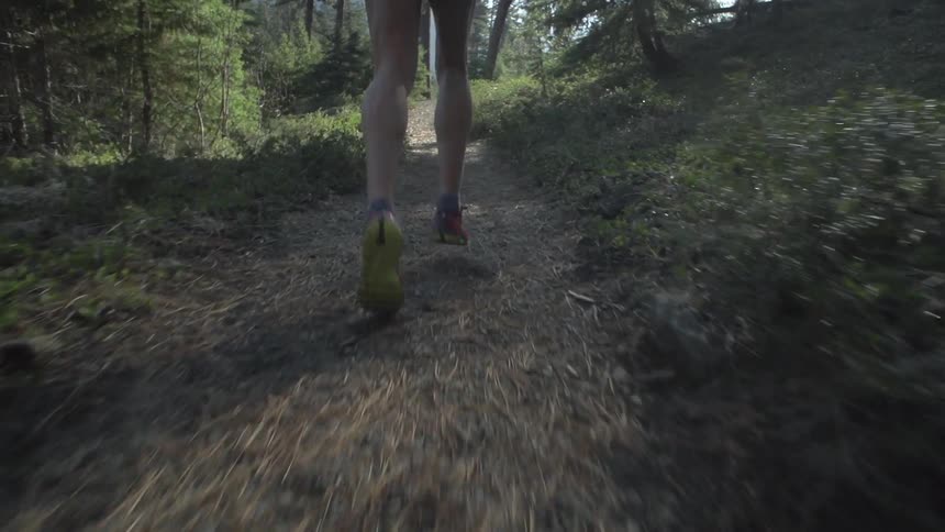 Man running down a trail in a forest
