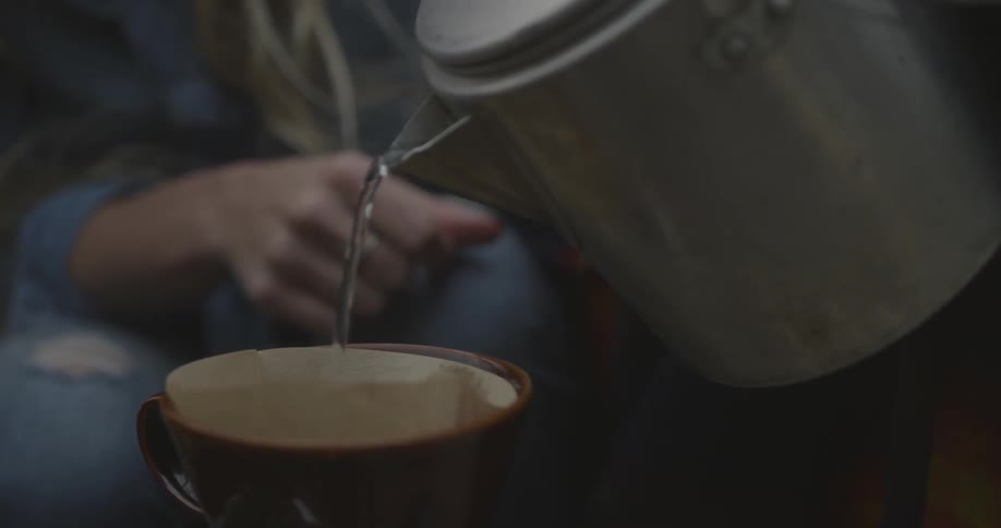 A person is pouring a kettle into a mug