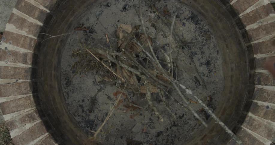 A person is putting branches in a campfire