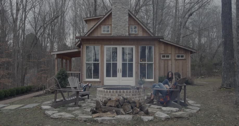 Two women chat by an outdoor fire pit on a chilly day