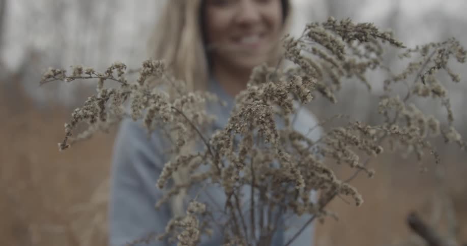 A woman holds up picked flowers and smiles