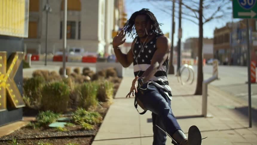 Man dancing on the sidewalk in the middle of a town