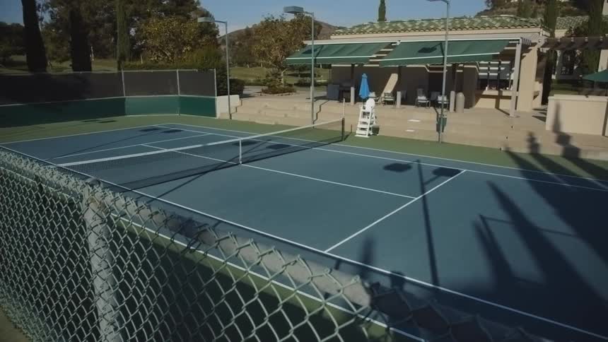 Slow pan of an empty tennis court on a sunny day