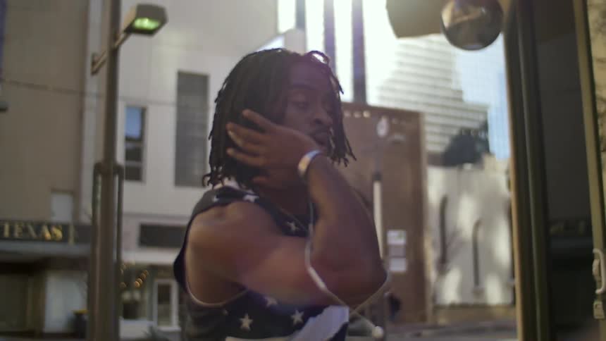 Man with dreadlocks spinning and gesturing on a city street