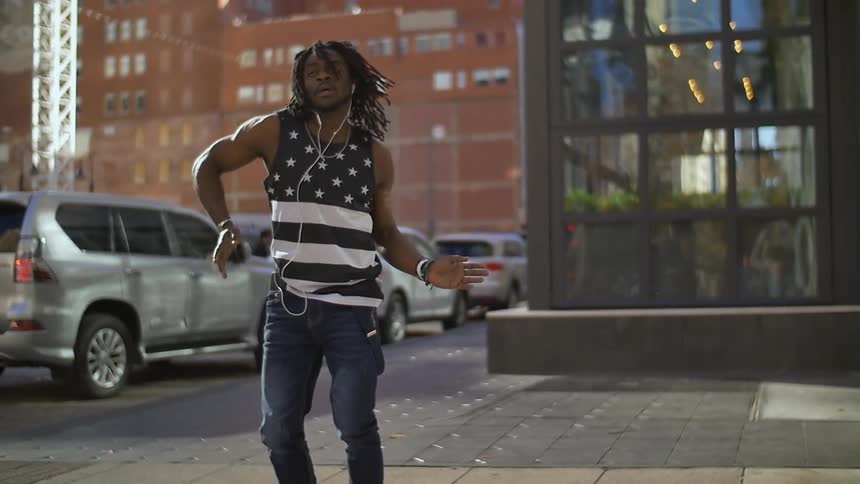 Man dancing interpretatively in a city next to a street
