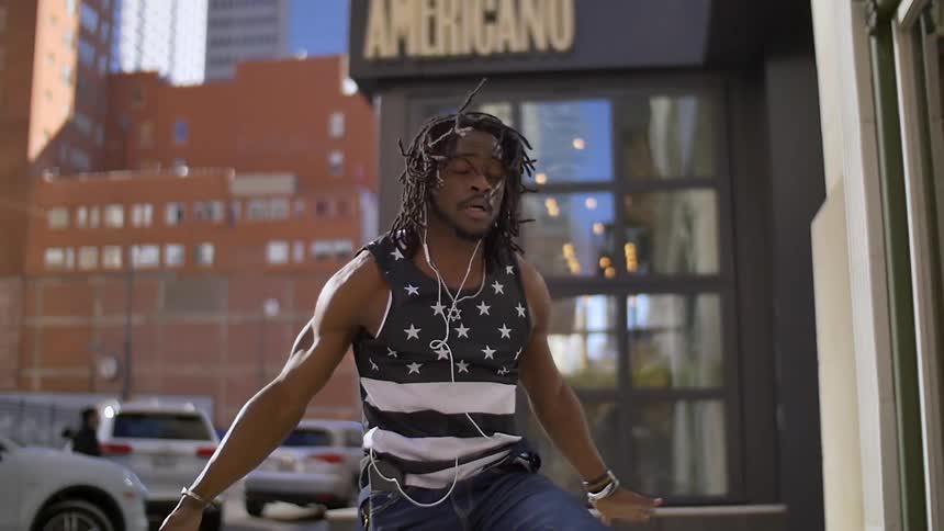 A man is dancing outside a building in the city