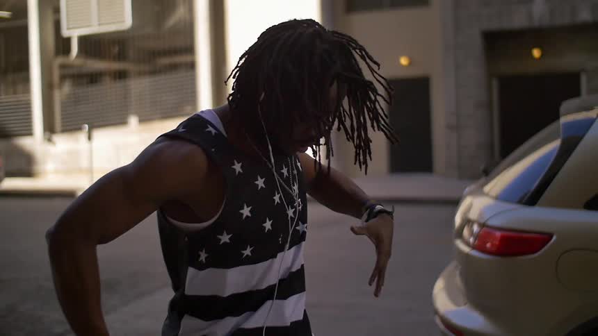 Man with dreadlocks spinning and jumping on a city street