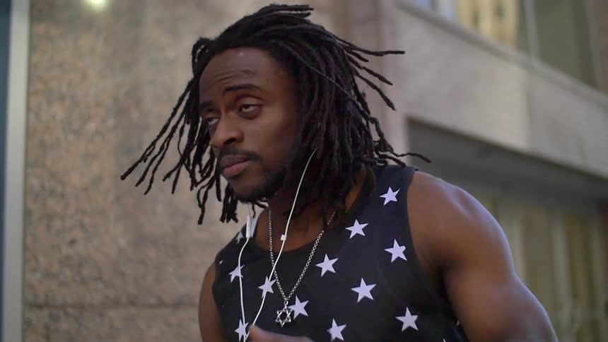 A man with earbuds in walks past a building