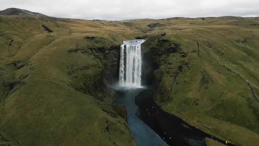 Aerial panorama of a greenish mountain valley with a large waterfall