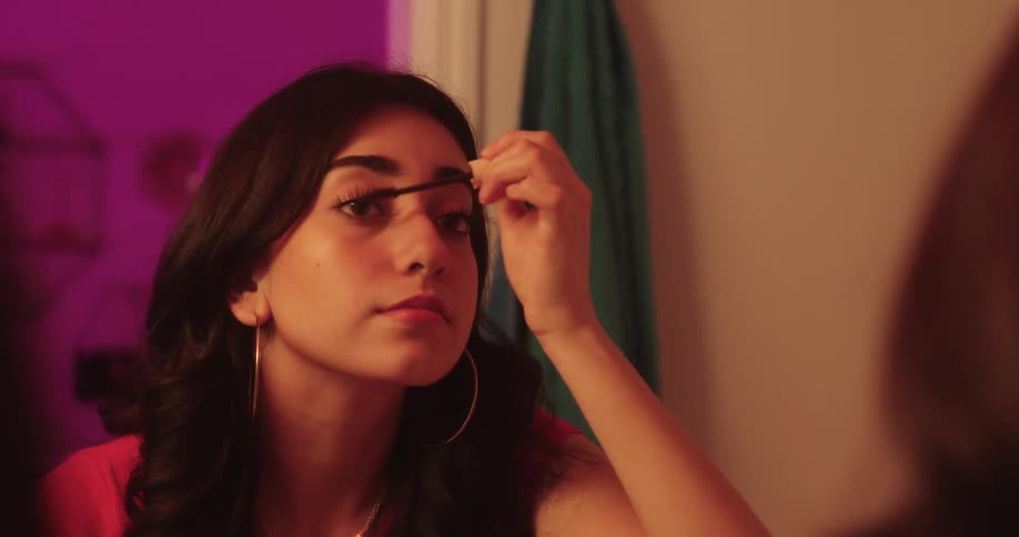 Woman applying makeup to her eyelashes in front of the mirror