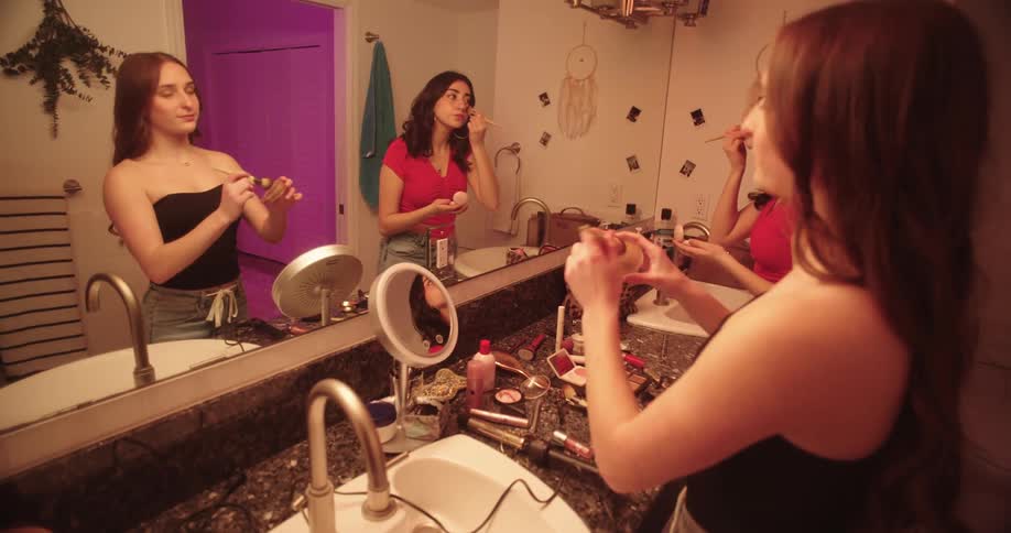 Teenage girls applying makeup in the bathroom at home