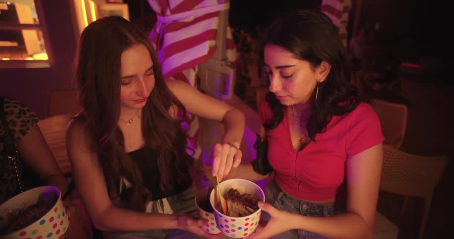 Three friends sitting in a restaurant at night eating ice cream
