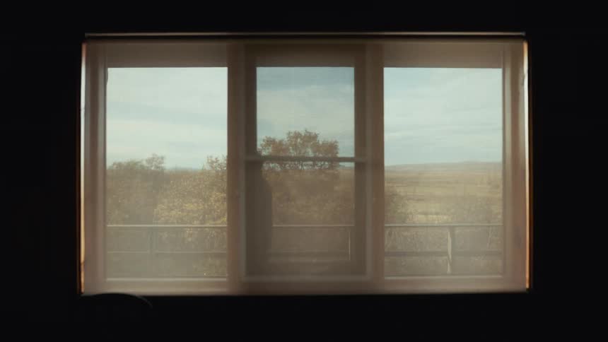 Man walking in outdoor hallway seen through window