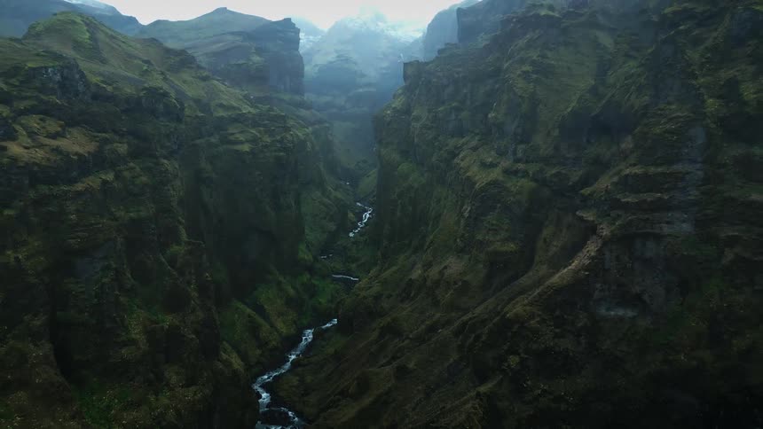A small stream runs through the tall mountains